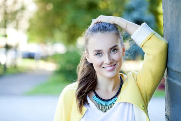 幸福的年轻女人在黄色的外套，在秋季街头 — 图库照片