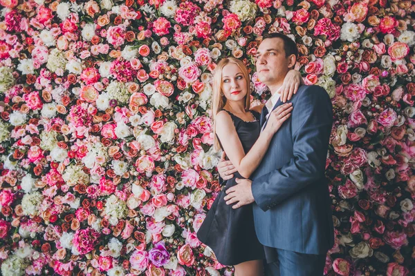 Loving couple in the studio flowers wall — Stock Photo, Image