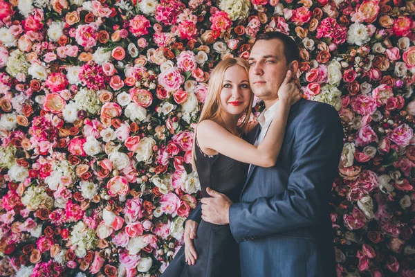 Loving couple in the studio flowers wall — Stock Photo, Image