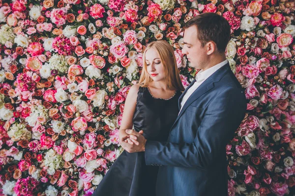 Loving couple in the studio flowers wall — Stock Photo, Image