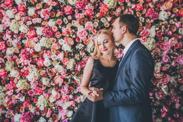 Casal amoroso na parede de flores estúdio — Fotografia de Stock