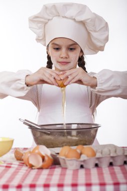 Küçük aşçı kız beyaz bir önlük yumurtaları derin bir tabak içinde tatili.