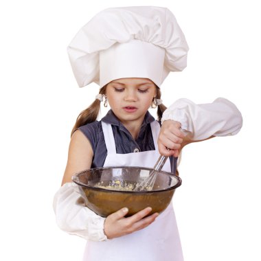 Küçük kız cook fırçalamak yumurta büyük bir tabak içinde kamçı.