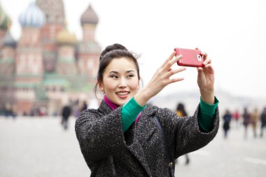 Young beautiful woman tourist taking pictures on mobile phone clipart