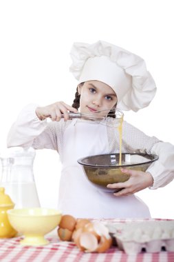 Küçük kız cook fırçalamak yumurta büyük bir tabak içinde kamçı.