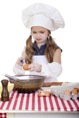 Küçük aşçı kız beyaz bir önlük yumurtaları derin bir tabak içinde tatili.