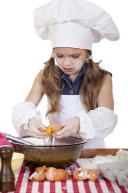 Küçük aşçı kız beyaz bir önlük yumurtaları derin bir tabak içinde tatili.