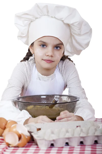 Niña en un delantal blanco se rompe cerca del plato con huevos — Foto de Stock