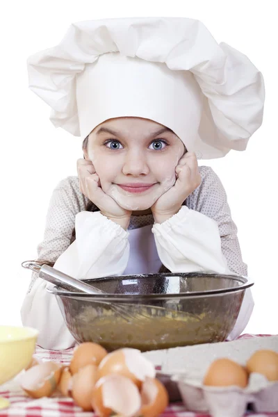 Little girl in a white apron breaks near the plate with eggs — Stock Photo, Image