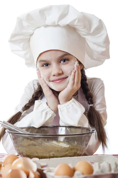 Little girl in a white apron breaks near the plate with eggs — Stock Photo, Image