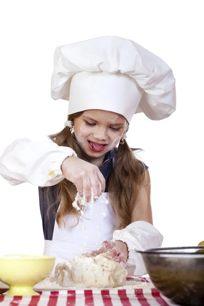 Dziewczynka w biały fartuch i czapkę kucharzy Zagnieść ciasto w th — Zdjęcie stockowe