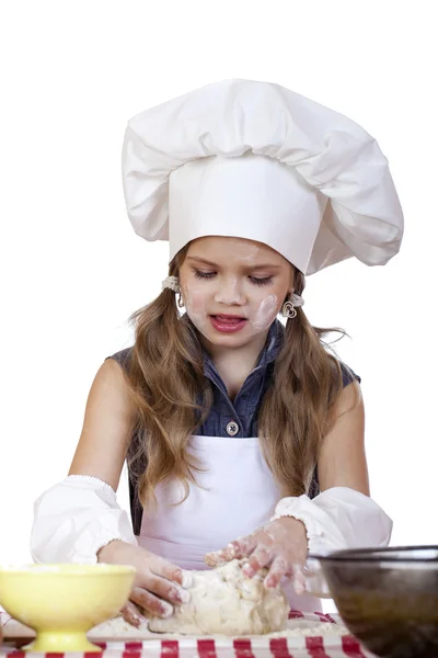 Niña en un delantal blanco y chefs sombrero amasar la masa en th — Foto de Stock