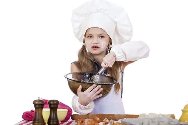 Menina cozinheiro chicotes bater ovos em um prato grande — Fotografia de Stock