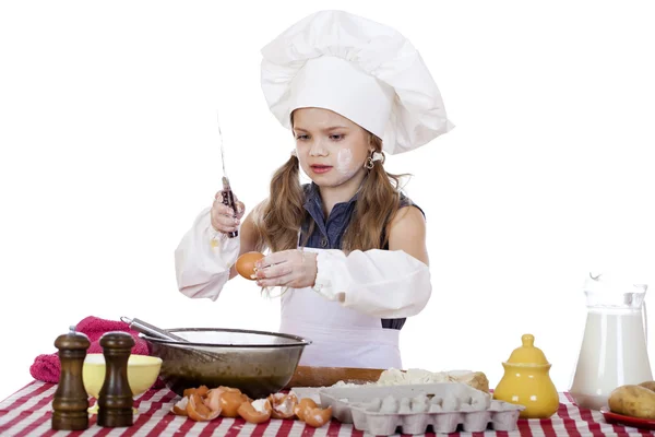 Little cook girl in a white apron breaks eggs in a deep dish — Stock Photo, Image