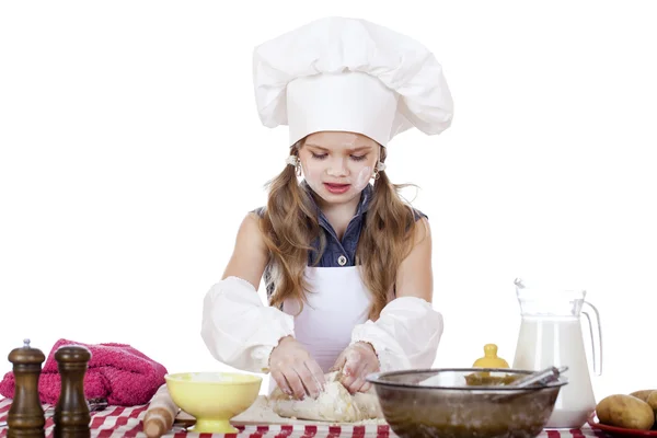 Menina em um avental branco e chapéu de chefs amassar a massa em th — Fotografia de Stock