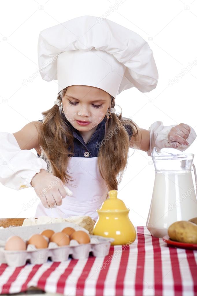 白いエプロンで少し料理女の子は深皿の卵を改します ストック写真 C Arkusha 白いエプロンで少し料理女の子は深皿の卵を改します ストック写真 C Arkusha