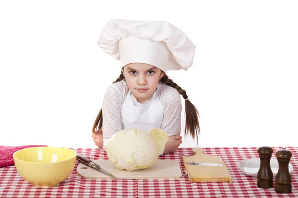 Portrait of a little girl in a white apron and chefs hat shred c — Stock Photo, Image