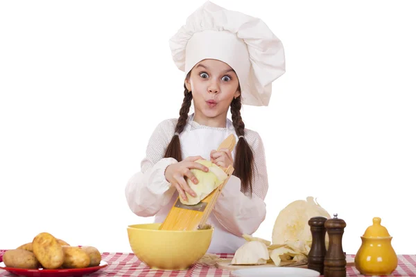 Portrait of a little girl in a white apron and chefs hat shred c — Stock Photo, Image