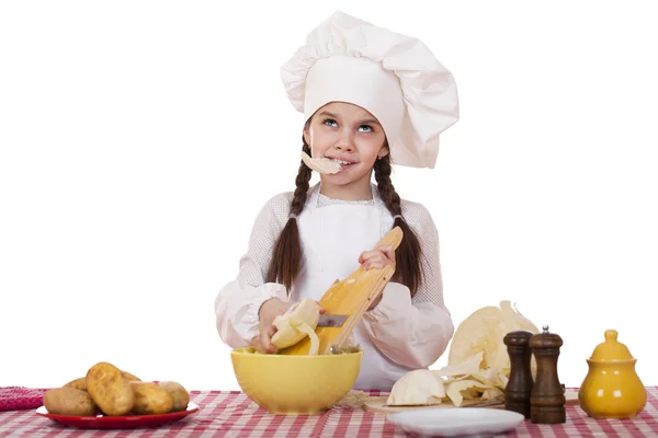 Portrait of a little girl in a white apron and chefs hat shred c — Stock Photo, Image