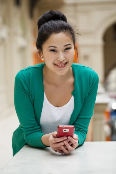 Jovem bela mulher asiática segurando um telefone celular — Fotografia de Stock