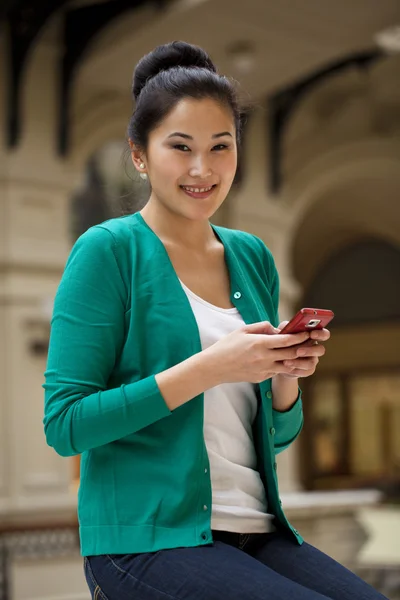 Jovem bela mulher asiática segurando um telefone celular — Fotografia de Stock