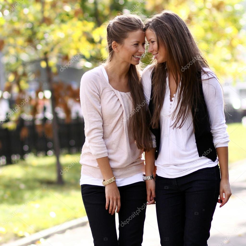 Two cheerful girls twins, in the street 