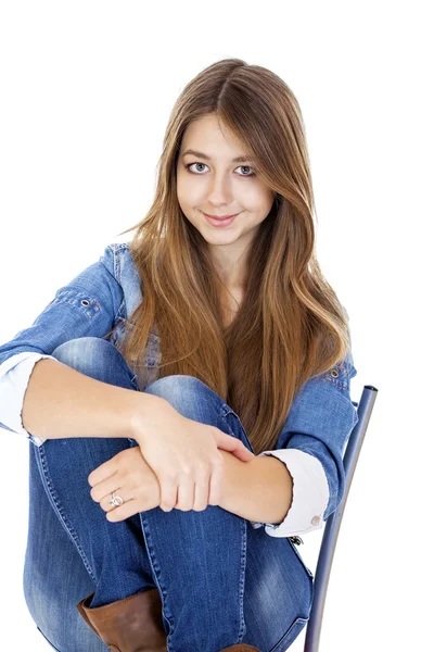 Porträt eines jungen Mädchens in Jacke und blauer Jeans, das auf einem Chai sitzt — Stockfoto