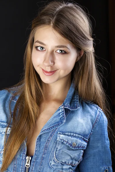 Retrato menina em uma jaqueta de jeans azul no estúdio escuro — Fotografia de Stock