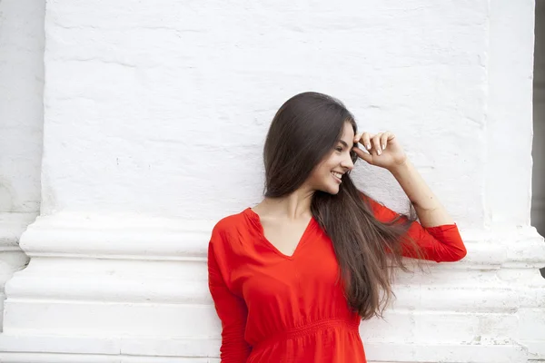 Boldog, fiatal nő, piros ruhás, a háttérben egy blokk — Stock Fotó