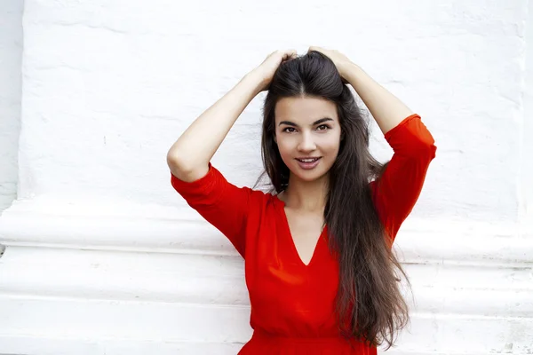 Mujer joven feliz en vestido rojo sobre el fondo de un bloque —  Fotos de Stock