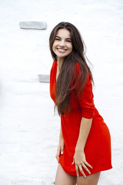 Happy young woman in red dress against the background of a block — Stock Photo, Image