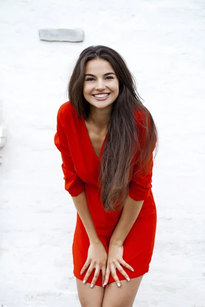 Happy young woman in red dress against the background of a block — Stock Photo, Image