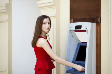 Bir otomatik vezne makinesi kullanarak Kırmızı elbiseli genç kadın 