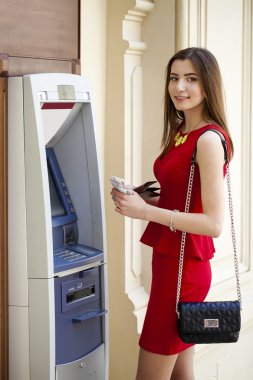 Bir otomatik vezne makinesi kullanarak Kırmızı elbiseli genç kadın 
