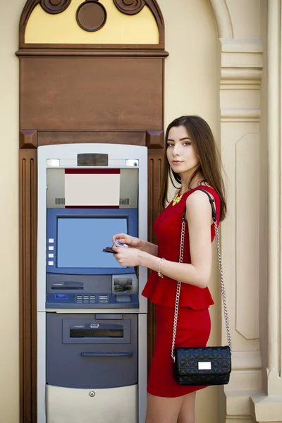 Молодая женщина в красном платье с помощью автомата кассира — стоковое фото