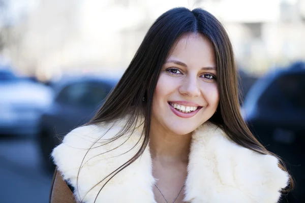 Happy young girl in sheepskin coat on a background of the city Royalty Free Stock Images