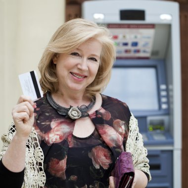 Olgun sarışın kadın Atm yakınındaki elinde kredi kartı ile