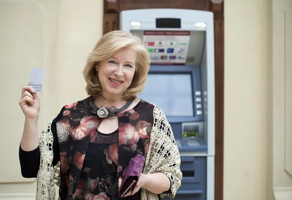Olgun sarışın kadın Atm yakınındaki elinde kredi kartı ile