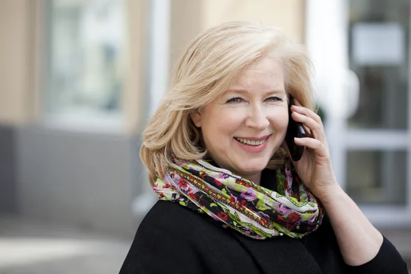 Volwassen mooie blonde vrouw eist op een mobiele telefoon — Stockfoto