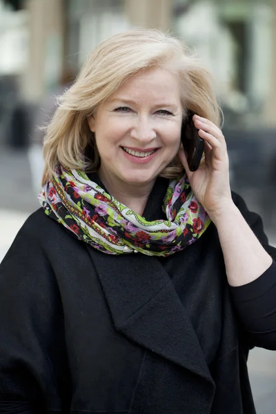 Mature beautiful blonde woman is calling on a cell phone — Stock Photo, Image