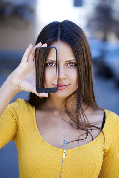 Young woman covers her face screen smartphone — Stock Photo, Image
