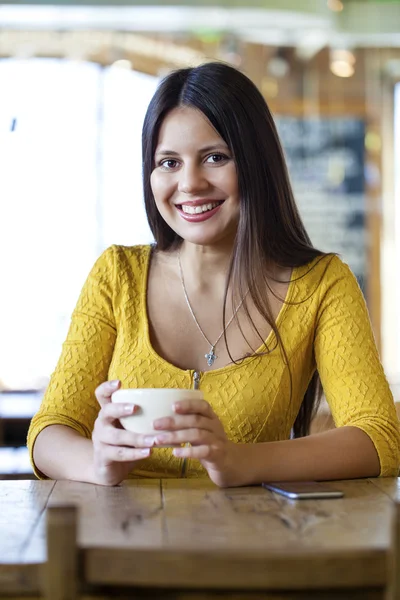 Mulher bonita sentada em uma cafeteria e beber chá — Fotografia de Stock