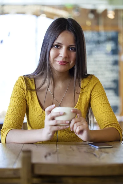 Mulher bonita sentada em uma cafeteria e beber chá — Fotografia de Stock