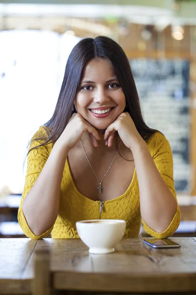 Bella giovane donna seduta in una caffetteria e bere il tè — Foto Stock