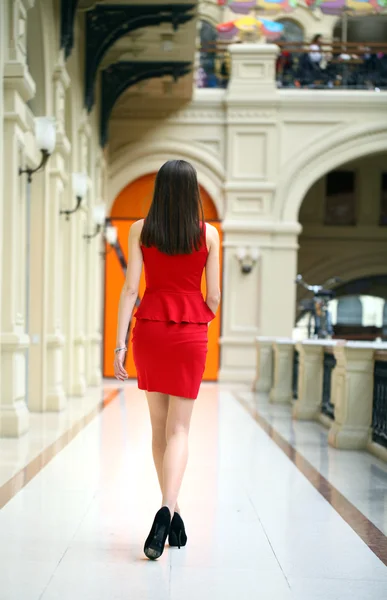 Mujer joven en vestido rojo caminando en la tienda —  Fotos de Stock