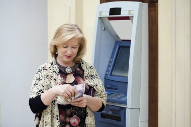 Olgun sarışın kadın yakınındaki Atm para sayma
