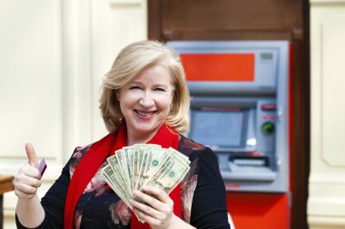 Olgun sarışın kadın yakınındaki Atm para sayma