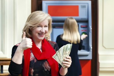 Olgun sarışın kadın yakınındaki Atm para sayma