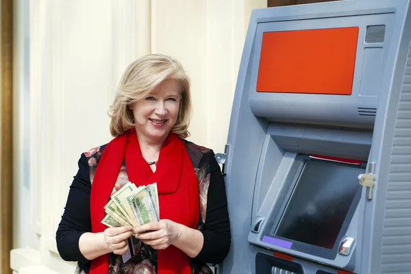 Mature blonde woman counting money near ATM — Stock Photo, Image