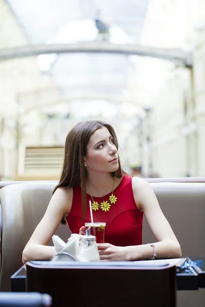 Menina morena bonita sentada em uma cafeteria — Fotografia de Stock